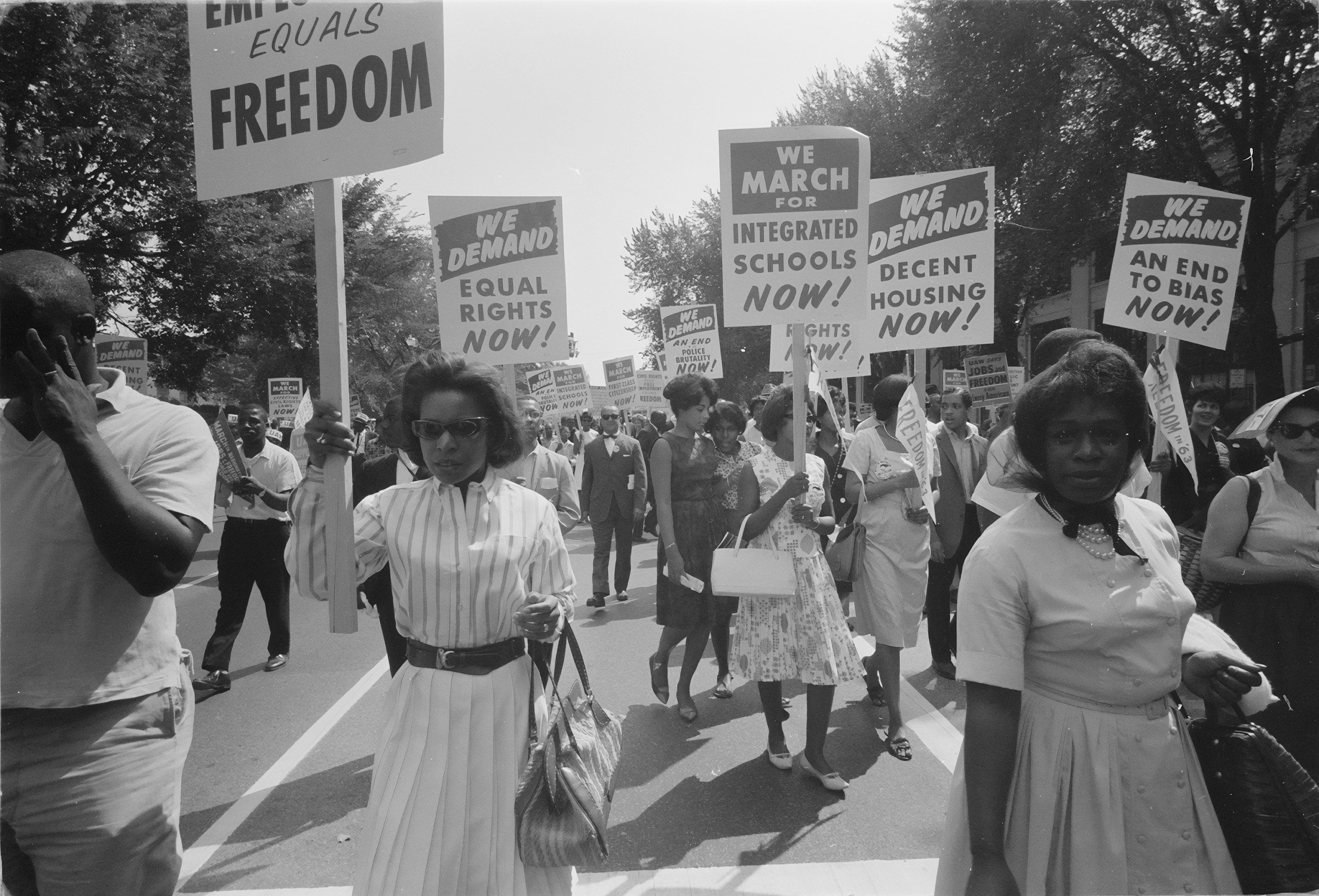 At the 1963 March on Washington for Jobs and Freedom protestors carry signs demanding decent housing, integrated schools, civil rights, freedom, and an end to bias.