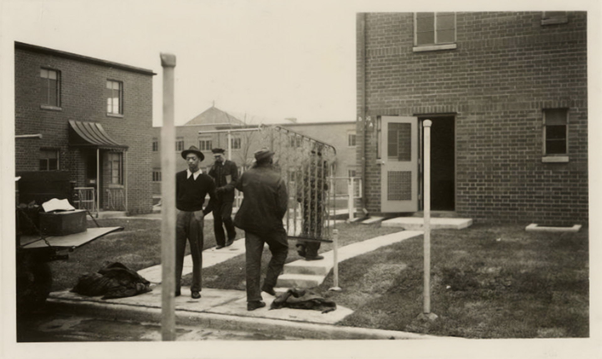 Dated May 13, 1940, photograph of two men carrying a bed frame into one of the units at Poindexter Village in Columbus, Ohio.